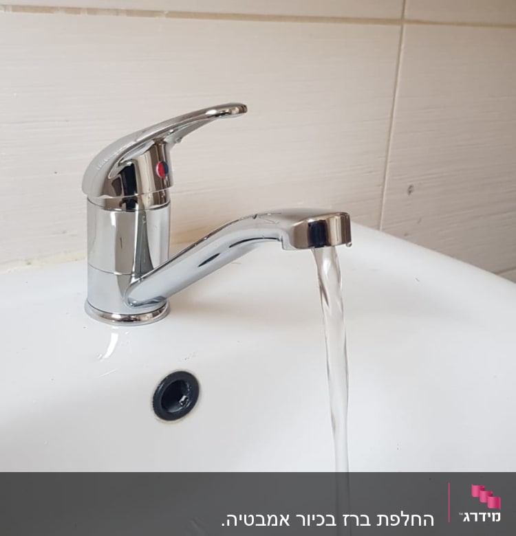 ברז כרום עם מים זורמים בכיור לבן